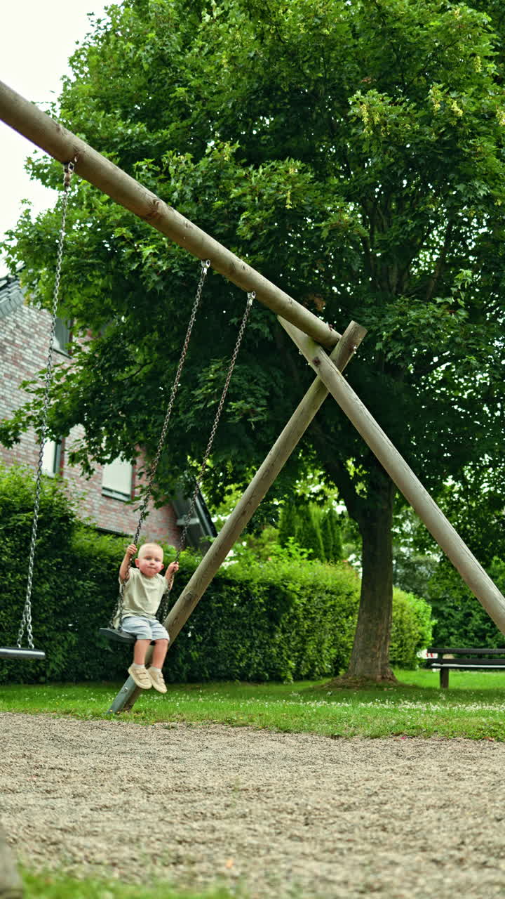 Niño alegre se columpia en el exterior. Un niño se columpia en un parque infantil. Entretenimiento para niños en un parque de la ciudad. El niño pequeño juega al aire libre. Desarrollo infantil.