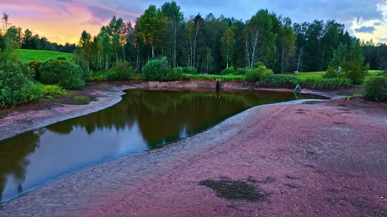Stagno di pesci prosciugato con acqua bassa e fitta foresta in lontananza al crepuscolo. - ripresa aerea