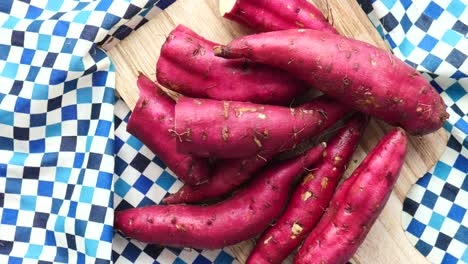 pile of purple sweet potatoes on a wooden cutting board