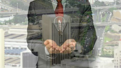 Animation-of-light-bulb-over-businessman-hands-and-cityscape-background