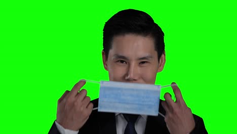 asian businessman wearing protective mask with green screen or chroma key background. the virus outbreak made everyone wear protective masks.