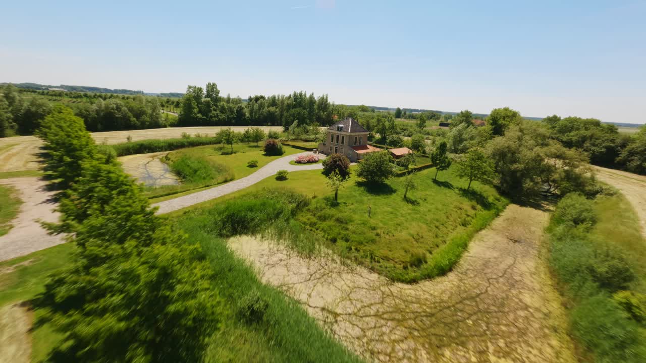 Lentävä FPV-drone puun läpi, paljastaen talon hollantilaisella maaseudulla.