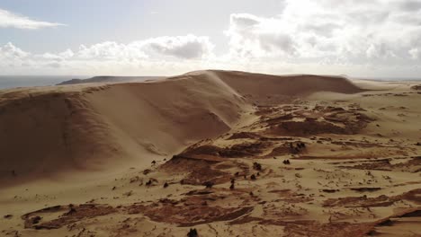 Iconic-golden-sand-Giant-Sand-Dunes-Ninety-Mile-Beach-aerial-backward-Attraction-made-by-nature,-New-Zealand