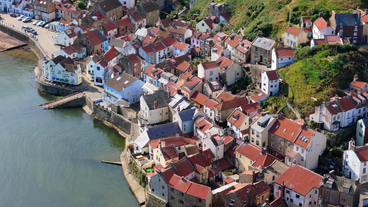 Veduta aerea con drone del porto di Staithes sulla costa del North Yorkshire con fiume, case e barche in una soleggiata mattina di agosto, in estate.