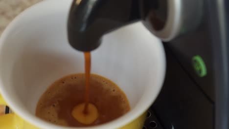 pulgar presionando el botón parpadeante y activando una máquina de espresso que vierte café recién humeante en una taza grande