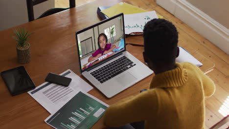 maestra afroamericana sentada en un escritorio usando una computadora portátil teniendo una lección escolar en línea