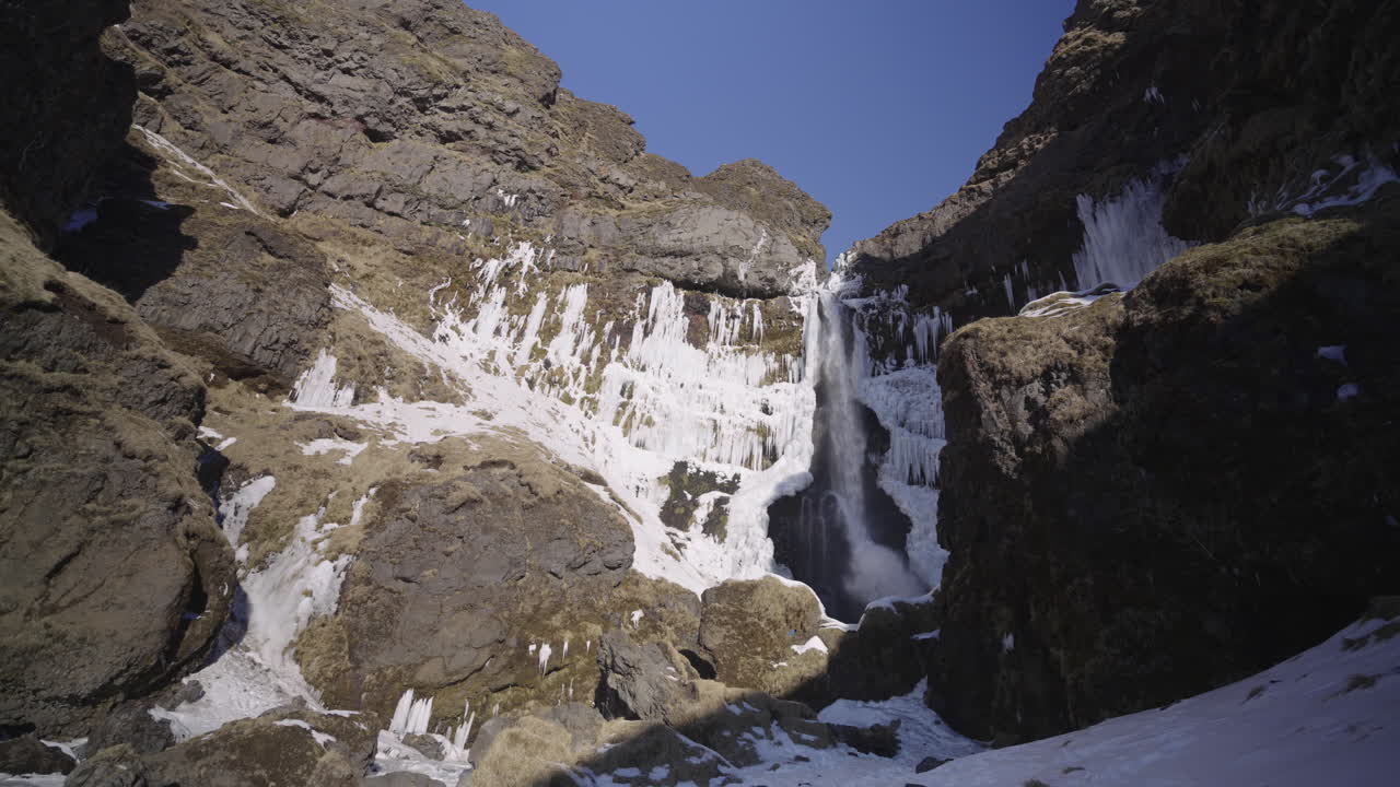 cañón de cascada escondido en islandia durante un día soleado con nieve y hielo