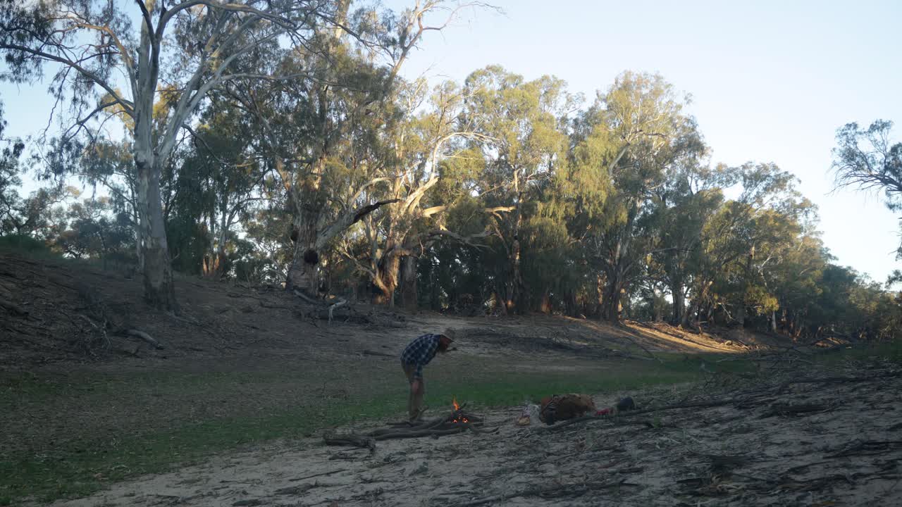 Traditional bushman makes a fire in a dry river bed in the Australian Outback.