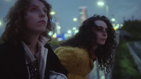 girls leaning on railing on dark city street