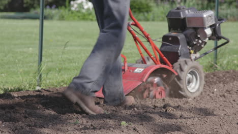 man uses a rototiller to till his garden