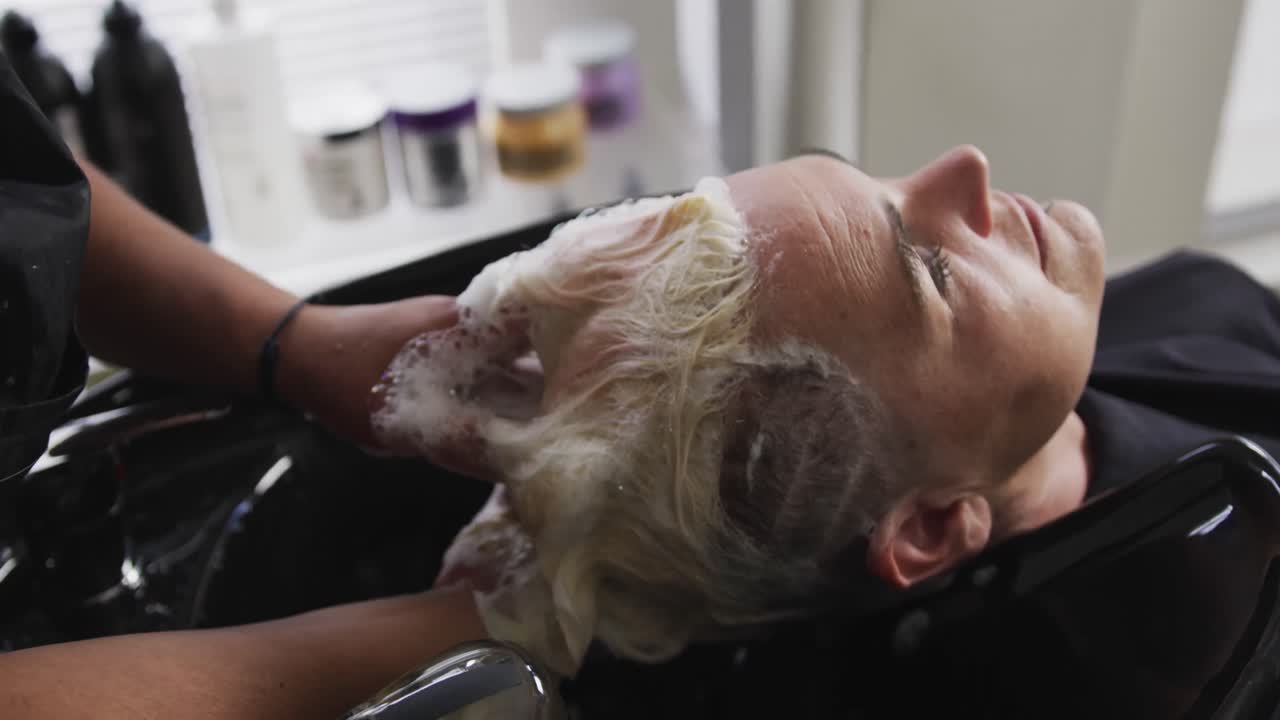 Rear view woman having her hair washed by a hairdresser