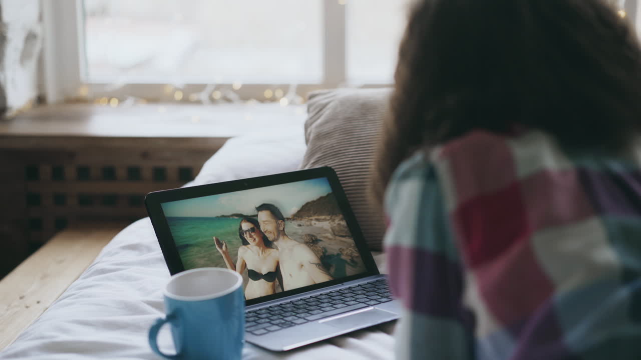 Woman watching a photo of a couple on a beach on her laptop