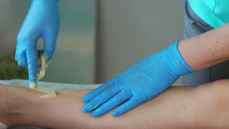 un primer plano de la mano en guantes de goma se aplica a la pasta de depilación y por tecnología especial shugaring elimina el pelo