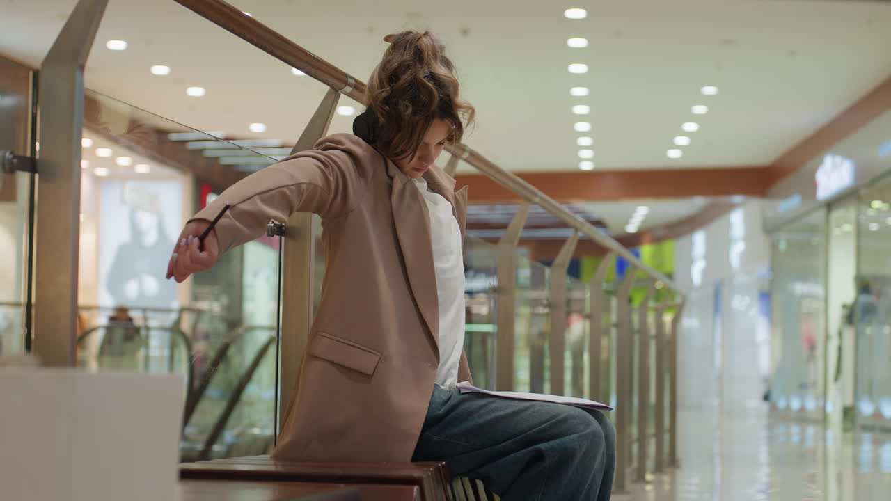 Una mujer alegre escucha música mientras compra; una joven relajada se divierte con la música en un centro comercial; una mujer joven y jovial disfruta de la experiencia de compra acompañada de su música favorita