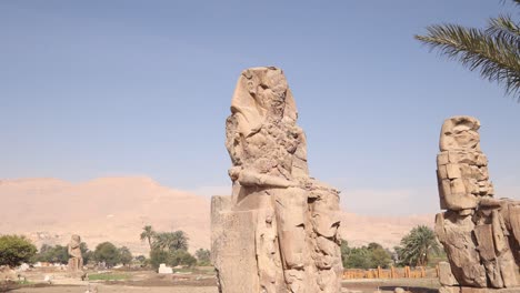 ruinas de las dos estatuas gigantes de faraón con montañas en el fondo en los colosos de memnon en luxor, egipto