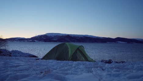 camping tent by the river on a cold night in winter