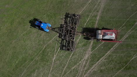 A-tracking-top-down-shot-of-a-grain-drill-seeder-machine-at-the-farm-while-roaming-the-field