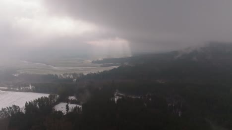 aerial view of light coming through clouds. winter panorama of forest and fields landscape in czech republic