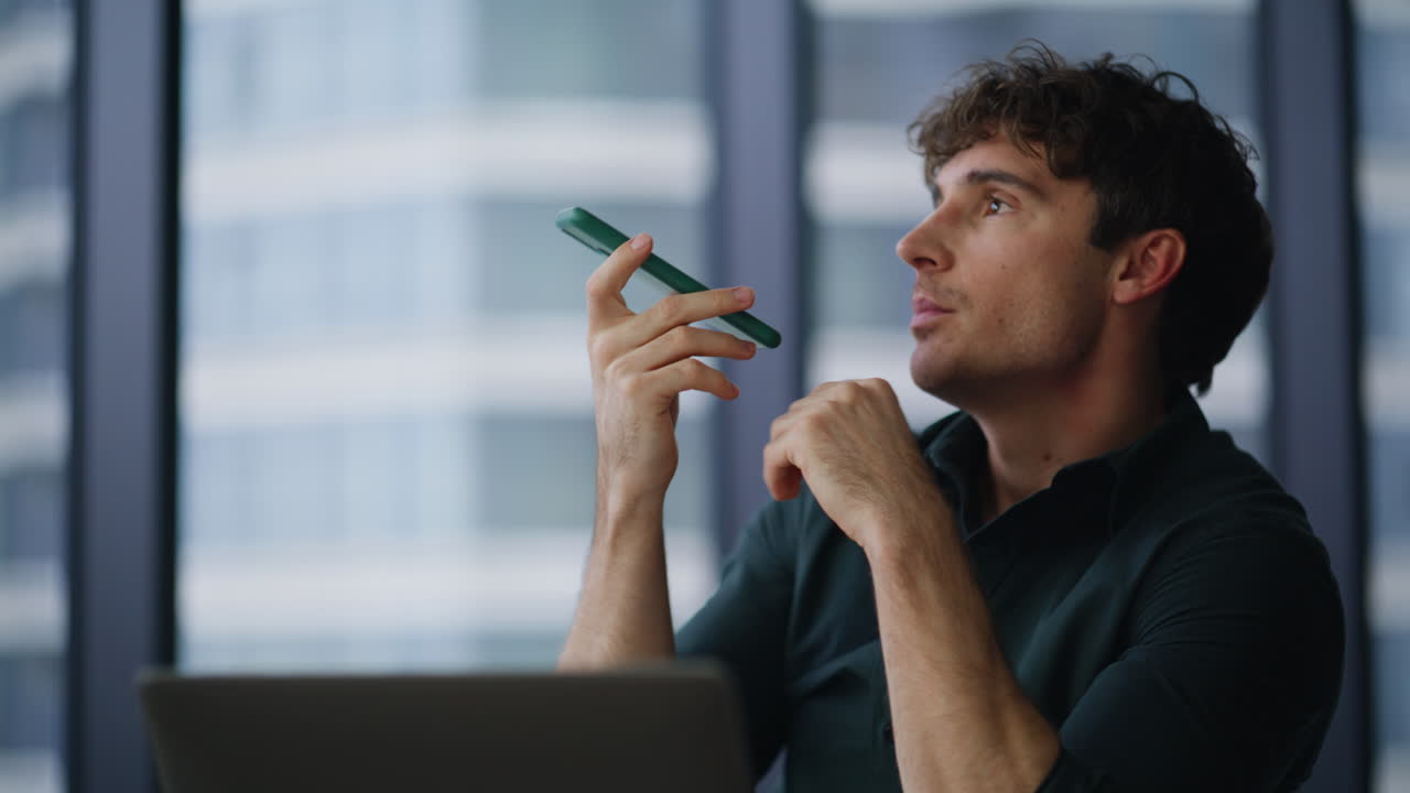 Freelancer dictating voice message at smartphone sitting agency office closeup