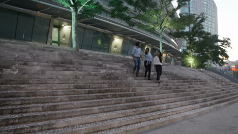 three young business people coming down by stairs while talking