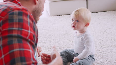 toddler son sits watching his dad play ukulele and sing