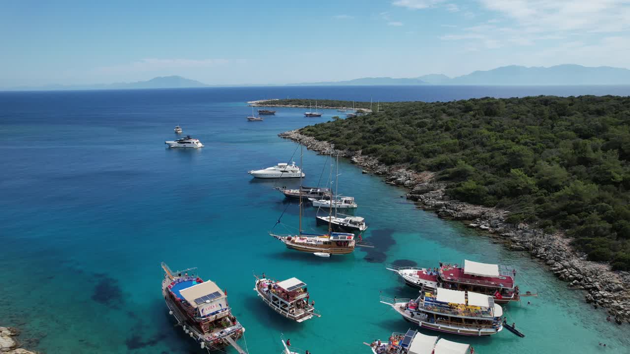 Drone of boats parked in shallow crystal blue waters on the Turkish Riviera in Bodrum