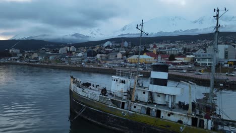 aerial view of a stranded ship with a town with snowy mountains in the background