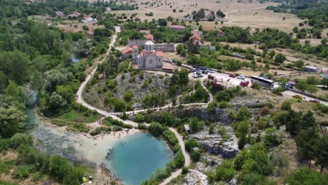 drone pans from above down to the famous cetina spring in croatia, a small church towers over the lake