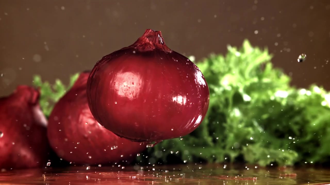 Rødløg falder i slowmotion med vandsprøjt