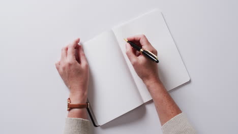 handschrift mit stift auf buch mit kopierraum auf weißem hintergrund in langsamer bewegung