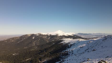 despegue de un dron aéreo desde un camino nevado que revela una interminable cadena montañosa salvaje cubierta de nieve