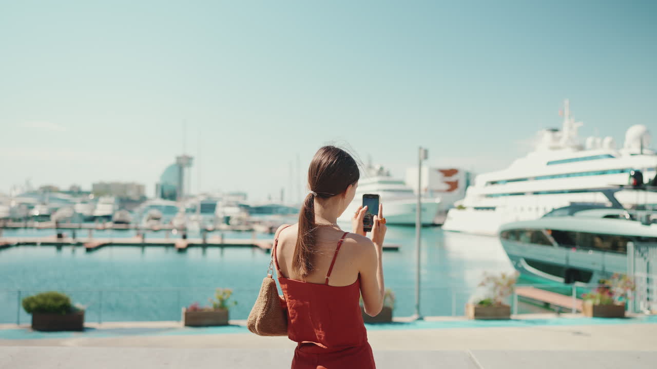 Woman taking pictures of yachts in Barcelona harbor