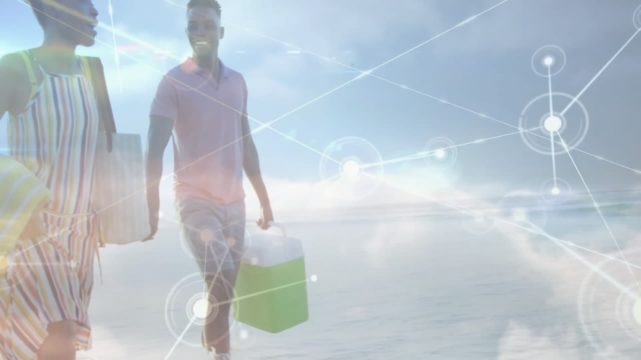 Beach couple walking barefoot holding cooler, tote bag and towel, showing network overlay for tech