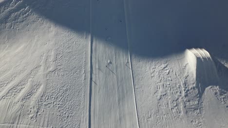 aerial view of a ski slope with skiers and snowboarders, snow-covered mountains