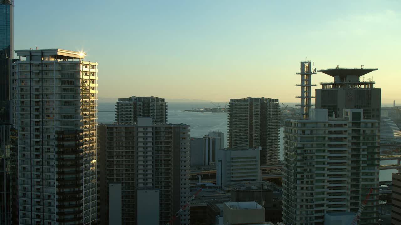 Vista da hora dourada de edifícios altos e oceano em cidade costeira