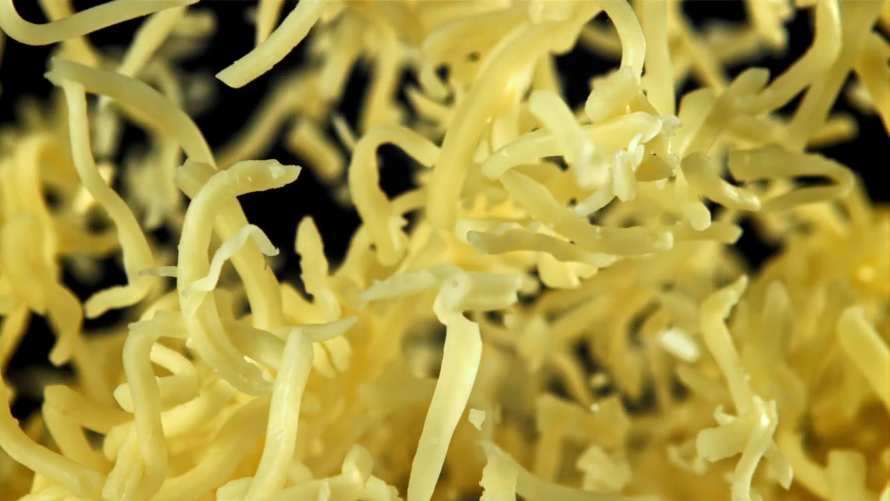 Shredded Cheese Falling in Slow Motion on Black Background