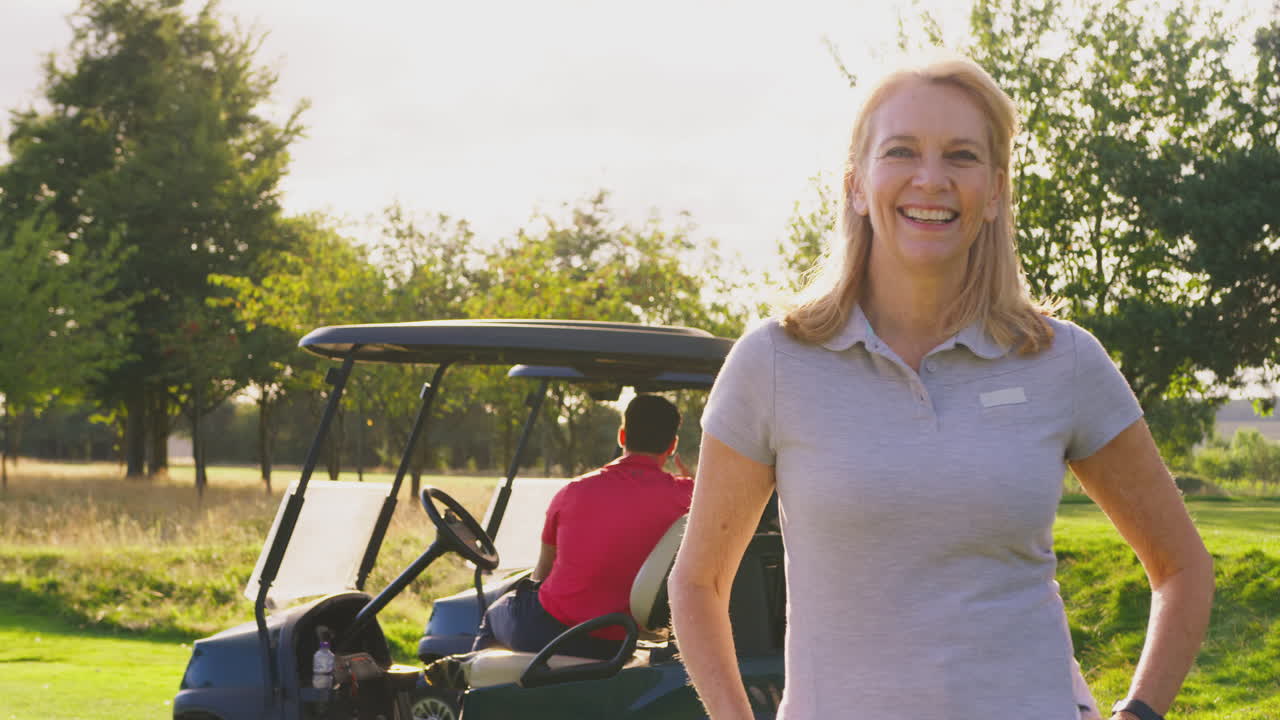 Ritratto di golfista donna matura sorridente in piedi vicino al buggy su un campo da golf
