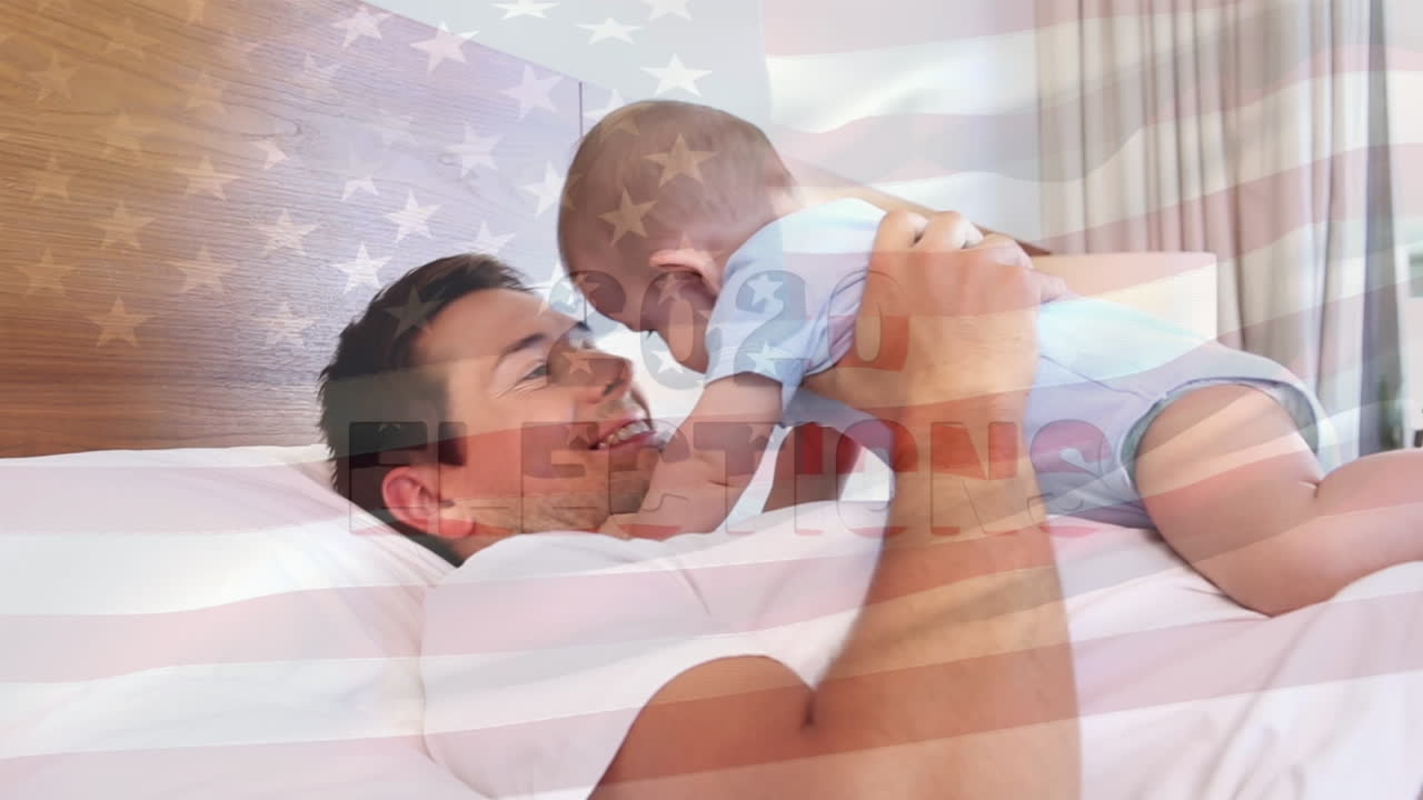 Animasjon av amerikansk flagg som vaier over en lykkelig kaukasisk far og baby som leker på seng
