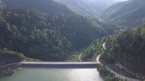 Aerial-shot-of-reservoir-amongst-the-valley-with-green-woodland-clear-skies