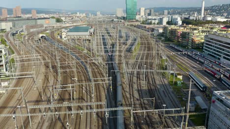 Aerial-Tracking-Shot-of-Train-Leaving-Zurich's-Central-Rail-Station-in-Summer