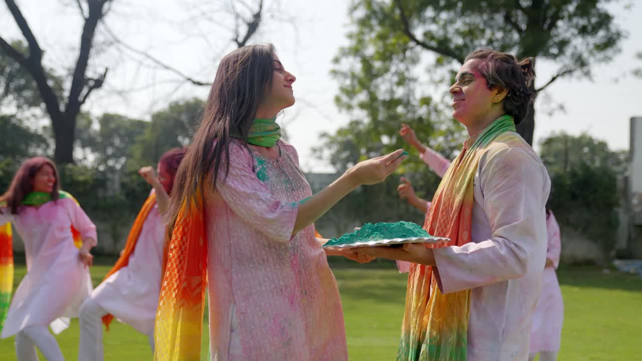 Adorable pareja india aplicándose colores de Holi en la cara