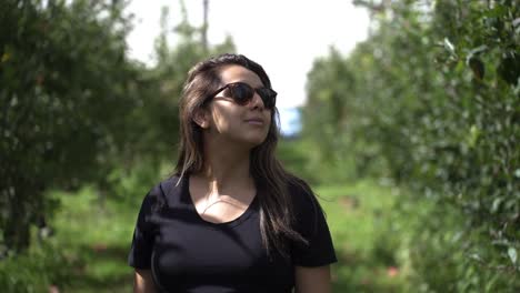 Close-Up-Of-Woman-Walking-Through-Fruit-Farm-And-Appreciating-Nature