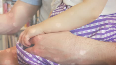 animation of hearts floating over midsection of caucasian father and child working on laptop