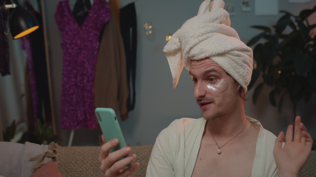 Man with towel and eye mask using smartphone