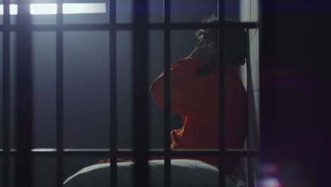 el prisionero se sienta en la cama y habla por teléfono en la celda de la prisión.