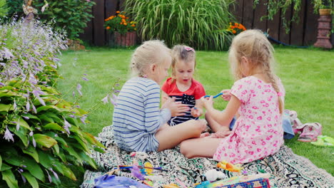 four girls playing in the yard sit and sculpt figures from clay