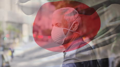 animation of flag of japan waving over man wearing face mask during covid 19 pandemic