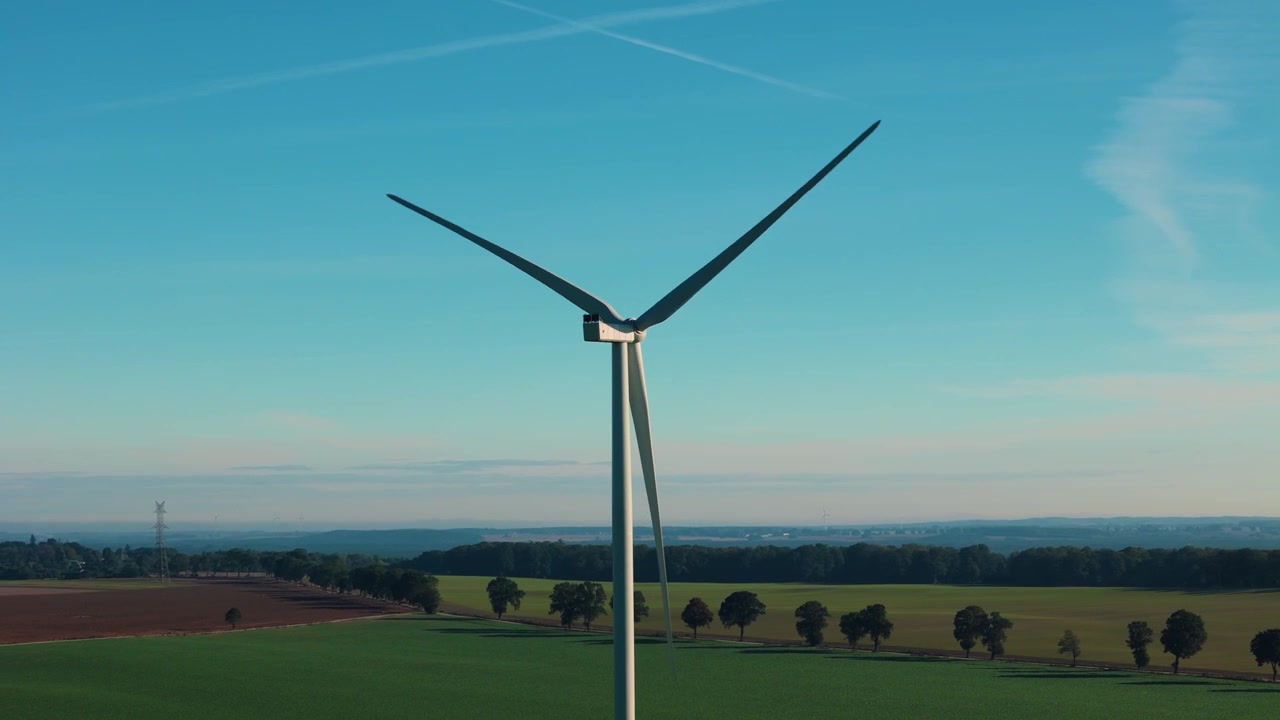 Singola turbina eolica con pale che girano su terreno agricolo