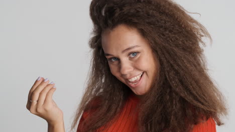 caucasian curly haired woman showing money gesture.