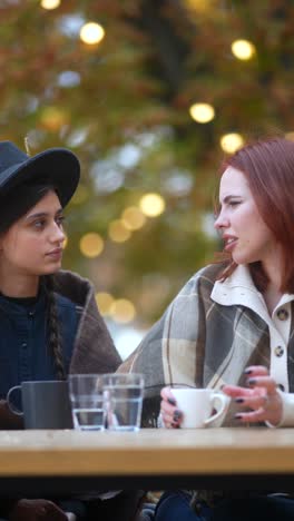 two women talking and enjoying drinks outdoor